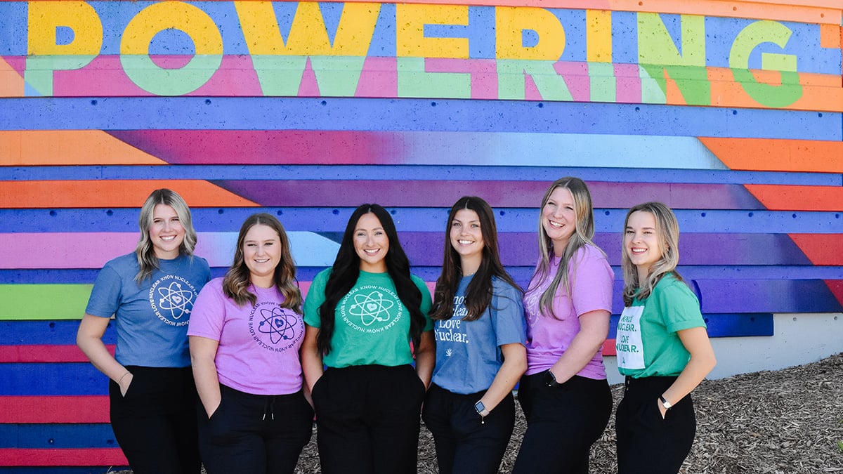 Group of six female students in front of ‘Powering’ sign. 